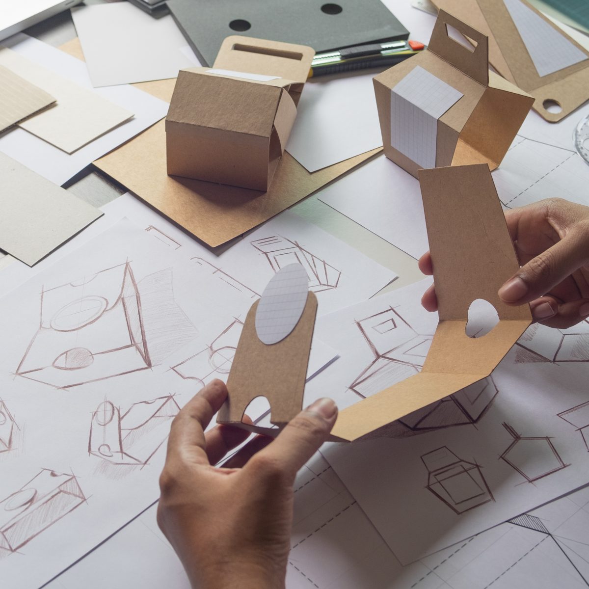 Designer sketching drawing design Brown craft cardboard paper product eco packaging mockup box development template package branding Label . designer studio concept .